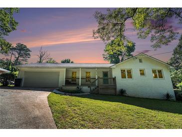 Charming white brick home featuring a covered front porch, attached garage and lush green lawn at 4384 Herschel Rd, College Park, GA 30337