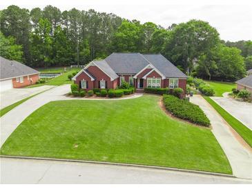 Charming brick home featuring lush green lawn, mature landscaping, and inviting entrance at 811 Ivy Ridge Dr, Loganville, GA 30052