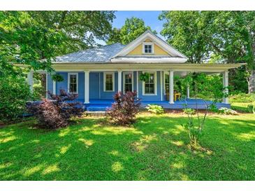 Charming blue home featuring a metal roof, a welcoming front porch, and lush landscaping at 7550 Fielder Rd, Jonesboro, GA 30236