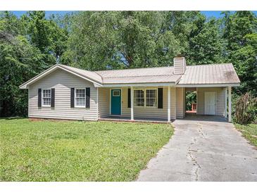 Charming one-story home with a metal roof, teal door, and well-maintained front yard at 10312 Waterford Ne Rd, Covington, GA 30014