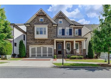 Charming two-story home featuring a covered porch, attached garage and manicured lawn at 828 Olmsted Ln, Duluth, GA 30097