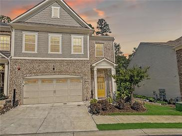 Charming two-story home with a brick facade, two-car garage, landscaped yard and a welcoming, bright yellow front door at 150 Holden Way, Woodstock, GA 30189