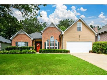 Charming home with a well-manicured lawn, brick accents, a two-car garage, and a welcoming red front door at 9013 Aldbury Dr, Locust Grove, GA 30248