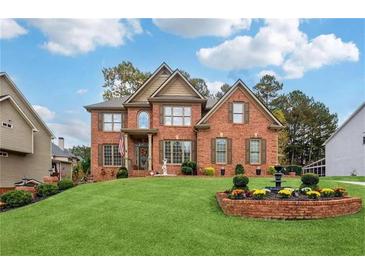 Stunning two-story brick home featuring manicured lawn and inviting front yard with beautiful garden and water feature at 1932 River Crest Way, Lawrenceville, GA 30045
