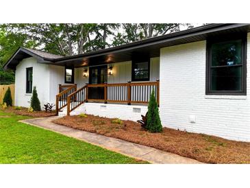 Charming home with a freshly painted white brick exterior, manicured lawn, and inviting front porch at 4296 Langdon Dr, Decatur, GA 30035
