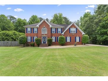 Beautiful two-story brick home with blue shutters and a well-manicured front yard with mature trees at 129 Crown Walk, Mcdonough, GA 30253