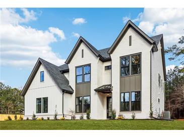 Striking white brick home featuring black trim, complemented by a well-manicured lawn and inviting curb appeal at 3735 Tamiami Trl, Cumming, GA 30041