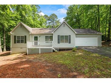 Charming single-story home with a white picket deck, an attached garage, and surrounded by lush greenery at 1154 Pinebrook Rd, Auburn, GA 30011