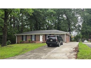Charming brick home featuring a well-maintained lawn and private driveway at 679 Winchester Ln, Norcross, GA 30071