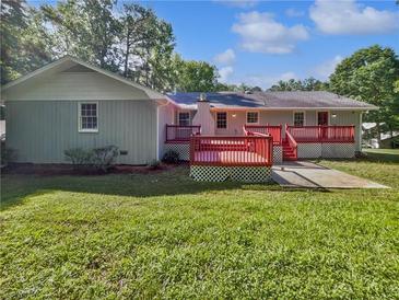 Lovely backyard featuring a red deck, spacious green grass and lush trees, perfect for outdoor entertaining at 5142 Golfbrook Ct, Stone Mountain, GA 30088
