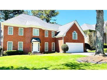 Charming brick home featuring a well-manicured lawn and attached two-car garage with a lovely tree in the front yard at 5633 Southland Dr, Stone Mountain, GA 30087