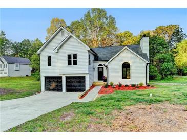 Charming two-story home with a well-manicured lawn, black garage doors, and inviting front entrance at 545 Woodrow Dr, Lawrenceville, GA 30043