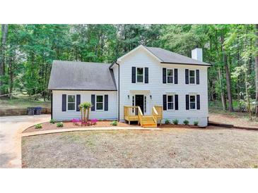 Charming two-story home with white siding, black shutters, and a landscaped front yard surrounded by trees at 545 Woodrow Dr, Lawrenceville, GA 30043