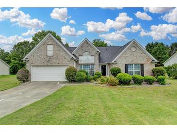 Charming single-Gathering home with a lush green lawn, well-manicured bushes, and a two-car garage at 3865 Portico Run Dr, Buford, GA 30519