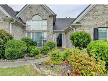 Charming brick home with a well-manicured front yard and lush landscaping at 3865 Portico Run Dr, Buford, GA 30519