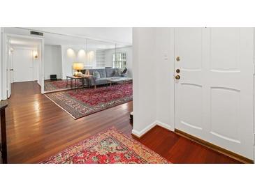 Inviting living room featuring hardwood floors, a large mirror, and a stylish red patterned rug at 52 Chaumont Nw Sq, Atlanta, GA 30327