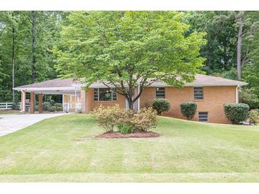 Charming brick home featuring mature landscaping, a welcoming covered carport, and a well-manicured lawn at 519 Beaver Ruin Nw Way, Lilburn, GA 30047