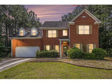 Charming two-story brick home with well-manicured lawn, mature trees, and an attached two-car garage at 2451 Broad River Pl, Ellenwood, GA 30294