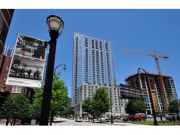 Modern high-rise building exterior with sleek glass facade and construction crane nearby on a bright sunny day at 855 Peachtree Ne St # 3205, Atlanta, GA 30308