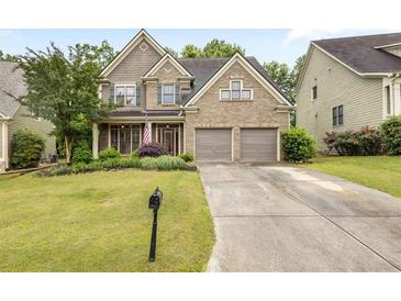Charming two-story brick home featuring a well-manicured lawn, mature trees, and a two-car garage at 1839 Tranquil Field Nw Dr, Acworth, GA 30102