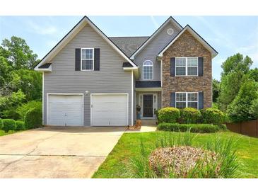 Charming two-story home featuring stone accents, a two-car garage, and a well-manicured front yard at 347 Cobblestone Court, Hampton, GA 30228