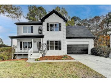 Charming two-story home with white brick, black shutters, an attached garage and a landscaped front yard at 1285 Cedar Brook Dr, Lawrenceville, GA 30043