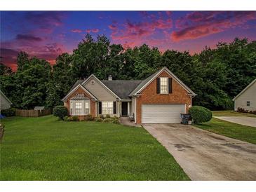 Charming brick home with a manicured front lawn and a two-car garage nestled among lush trees at 1290 Silverstone Trl, Jonesboro, GA 30238