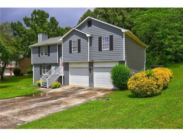 Split-level home featuring a two-car garage and front yard with shrubs and lawn at 4090 Mark Todd Ct, Hoschton, GA 30548