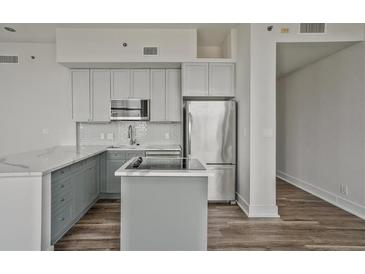 Modern kitchen features stainless steel appliances, gray cabinets, and a stylish island cooktop at 57 Forsyth Nw St # 14B, Atlanta, GA 30303