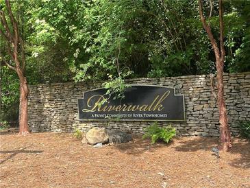 Stone sign at Riverwalk, a private community of River Townhomes with trees and greenery at 248 Riverview Trl, Roswell, GA 30075