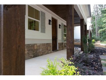 Covered porch with stone accents, wooden beams, and well-maintained landscaping enhances curb appeal at 3007 Holly St, Canton, GA 30115