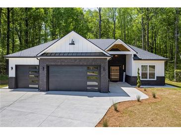 Charming home showcasing a black brick facade, modern garage doors and a well-manicured lawn at 632 Hunters Cove Ln., Loganville, GA 30052