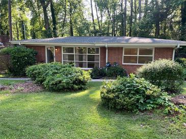 Charming brick home featuring large windows and lush landscaping in a serene, wooded setting at 1461 Alverado Way, Decatur, GA 30032