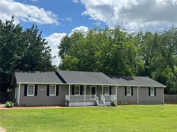 Charming single-story home with well-maintained lawn and inviting front porch and newly painted gray siding at 1810 King Mill Rd, Mcdonough, GA 30252