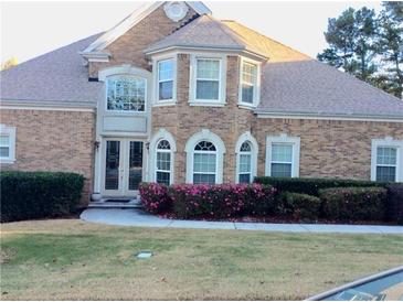 Charming brick home featuring a manicured lawn, blooming bushes, and elegant arched windows enhancing its curb appeal at 5430 Lemoyne Sw Dr, Atlanta, GA 30331