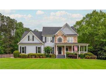 Charming two-story home with stone accents, a welcoming front porch, and a lush green lawn at 6610 Major Dr, Cumming, GA 30040