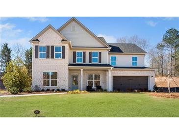 Two-story home with a well-manicured lawn, gray brick, black shutters, and a two-car garage at 5360 Hyde Rd, Cumming, GA 30040
