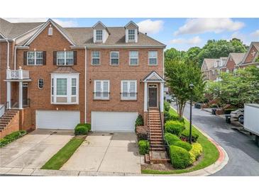 Brick townhouse with two-car garage, manicured landscaping, and inviting front entrance, radiating curb appeal at 6054 China Rose Ln, Duluth, GA 30097