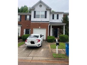 Two-story townhome with a brick facade, black shutters, and an attached garage and well-maintained landscaping at 116 Madeline Ct, Mcdonough, GA 30253