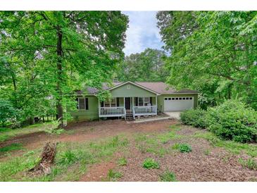 Ranch home with a charming front porch, nestled among lush trees in a serene setting at 1638 River Trce, Auburn, GA 30011