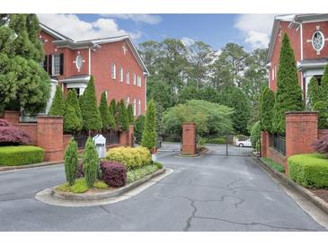 View of the gated entrance to a brick townhome community with manicured landscaping at 4298 Kingston Gate Cv, Chamblee, GA 30341