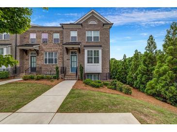 Brick townhome with manicured lawn, landscaping and a walkway leading to the front door at 4565 Sims Park Ovlk, Suwanee, GA 30024
