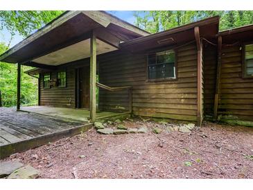 Rustic wood cabin exterior with a covered porch and natural surroundings in a wooded area at 418 Honey Suckle Ln, Stockbridge, GA 30281