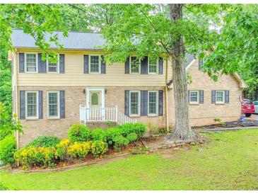 Charming two-story home with brick and vinyl siding and a well-manicured lawn and lush landscaping at 5293 Sandy Shoals Ln, Stone Mountain, GA 30087