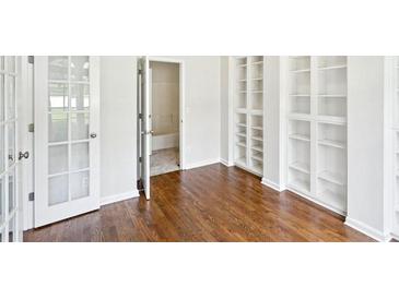 Bright bedroom with hardwood floors, built-in bookshelves, and french doors leading outside at 765 Brooks Cir, Stone Mountain, GA 30087