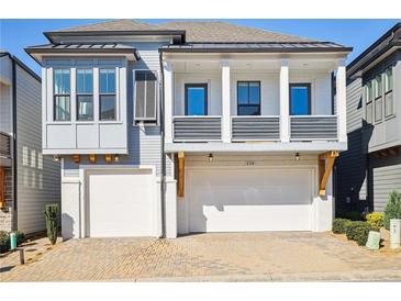 Beautiful two story home features brick driveway, dual garages, and charming balcony at 114 Village Green Ave, Woodstock, GA 30189