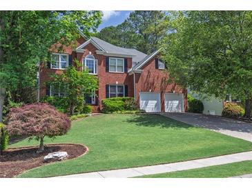 Charming two-story brick home featuring a well-manicured lawn, two-car garage, and classic architectural details at 320 Ironhill Trce, Woodstock, GA 30189