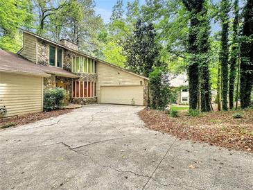 Stone and siding exterior of a home with an attached two-car garage and a long cracked concrete driveway at 10320 Crescent Ridge Dr, Roswell, GA 30076