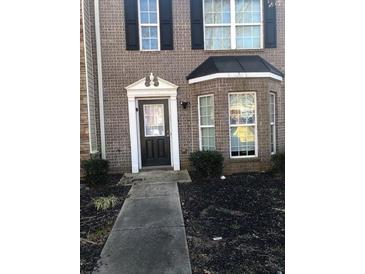 Charming brick home featuring a classic front door with decorative trim and a well-maintained front yard at 1843 Grove Way, Hampton, GA 30228