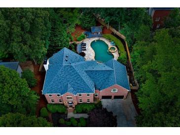 Stunning aerial view of a brick home featuring a beautiful pool and lush landscaping at 2882 Clary Hill Ne Dr, Roswell, GA 30075